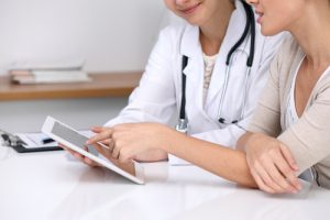 A patient and a doctor look at a tablet.