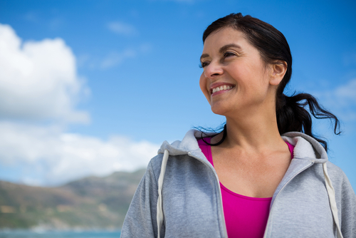 A smiling woman outdoors under a blue sky.