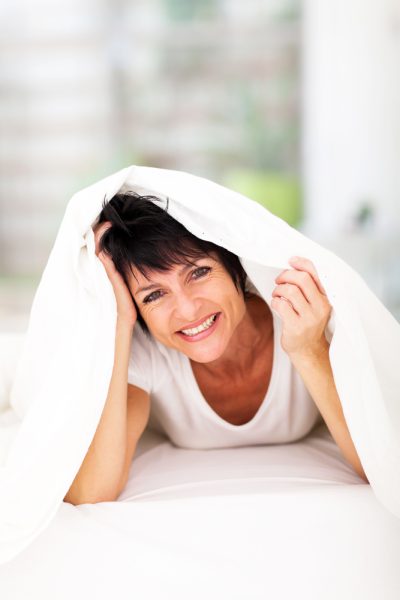 Fun,Middle,Aged,Woman,Lying,Under,Duvet,Laughing