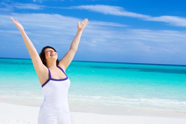 Happy,Woman,With,Raised,Hands,On,The,Beach